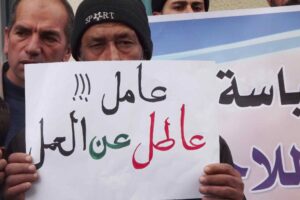 کارگر بحرینی که پلاکاردی با این عنوان در دست دارد:کارگری که از کار بیکار شده!